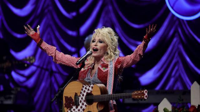 Photo de Dolly Parton en concert, haranguant la foule.